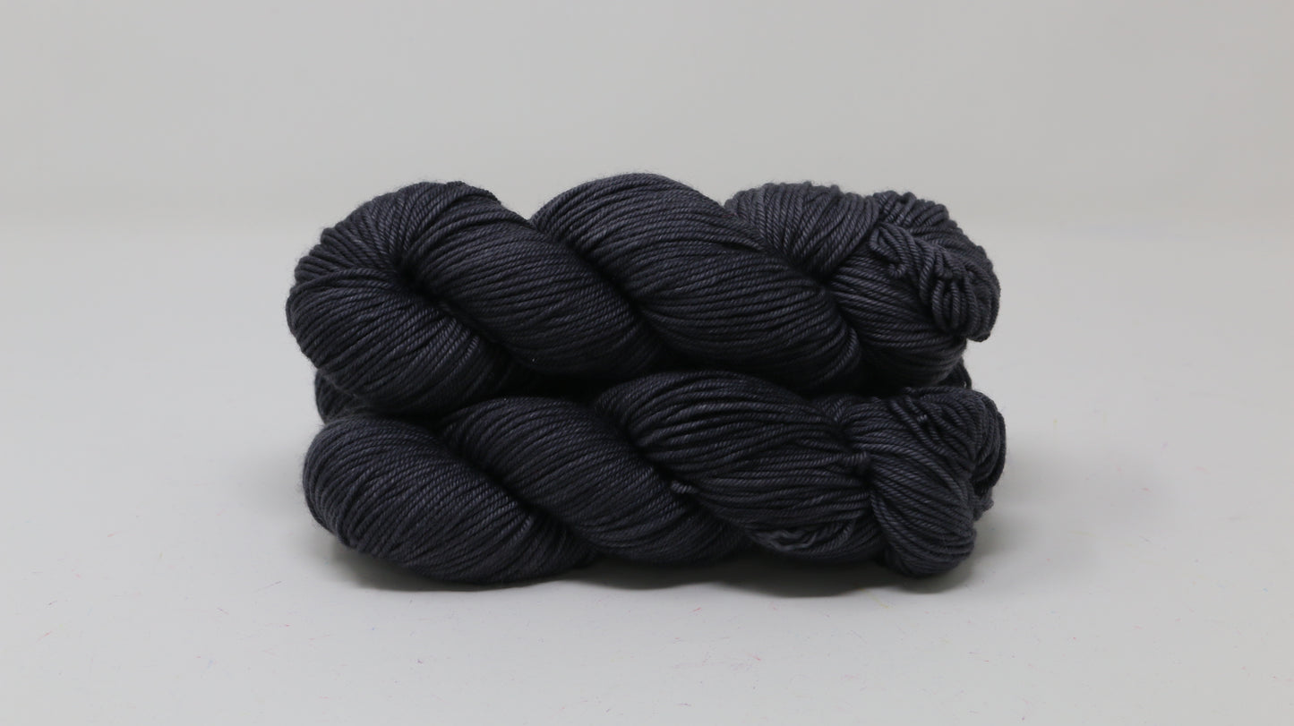 3 skeins of dark grey yarn on a white surface and background