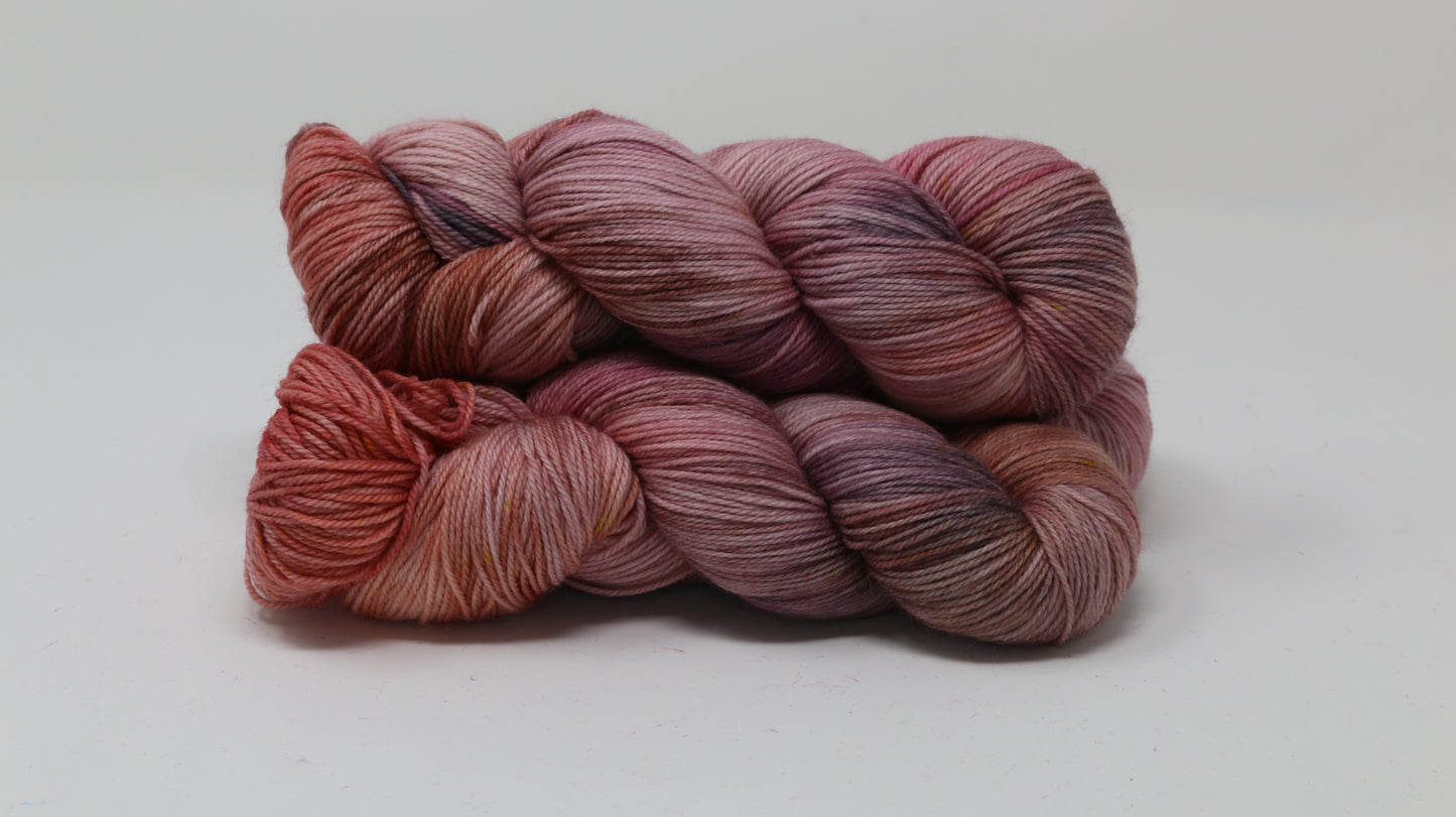 Three skeins of yarn in dusty rose, mauve, and terracotta tones