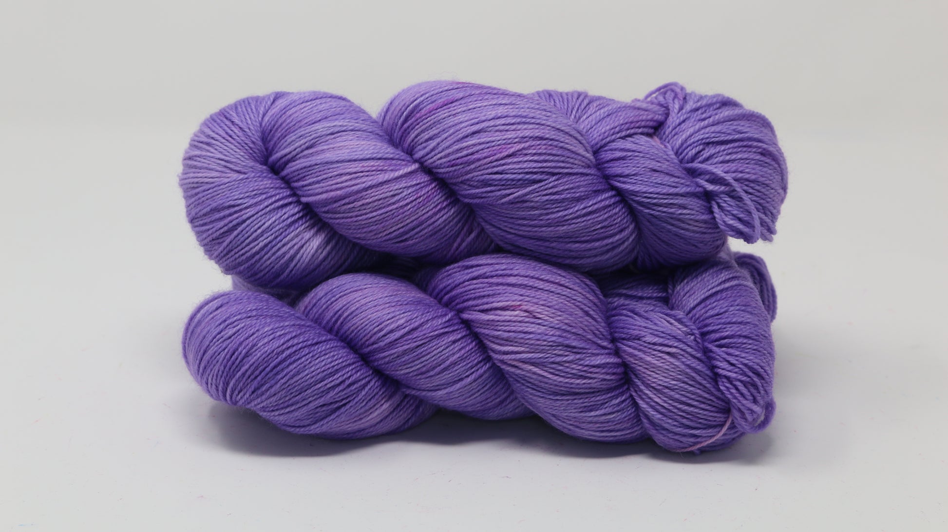 Stack of 3 purple skeins of yarn