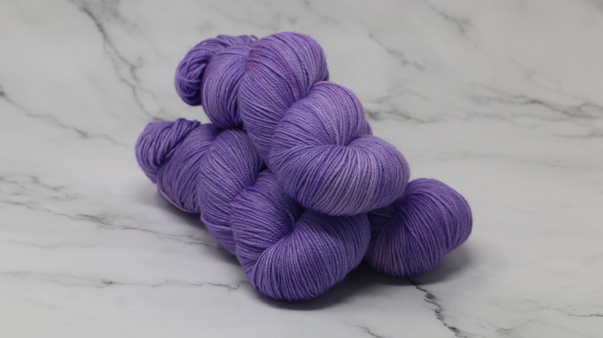 Stack of 3 purple skeins of yarn