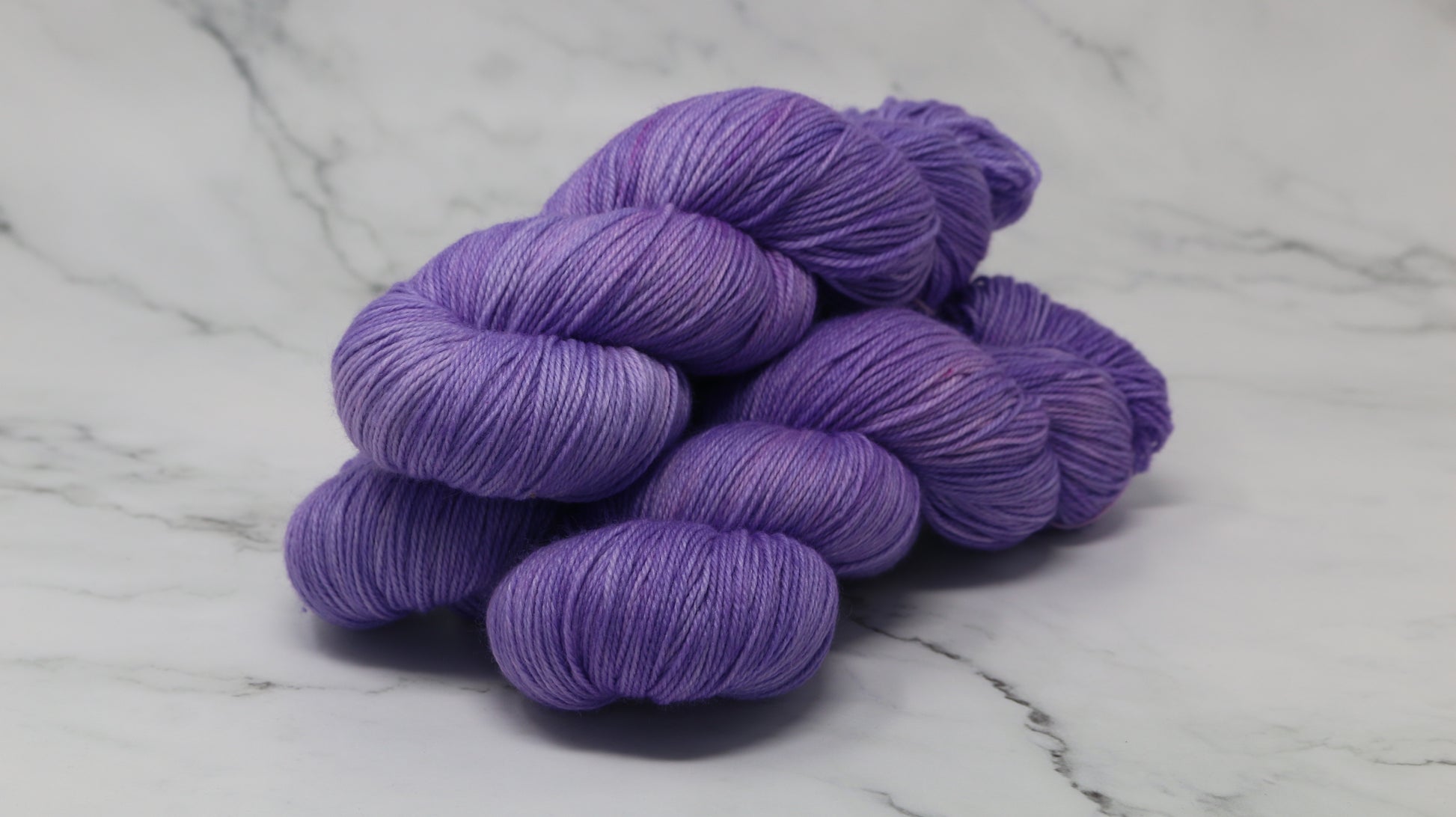 Stack of 3 purple skeins of yarn