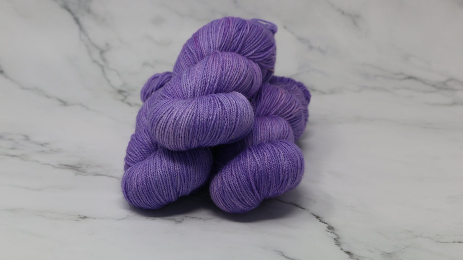 Stack of 3 purple skeins of yarn
