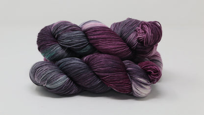 Three skeins of variegated yarn skeins in shades of purple, pink, green and dark gray
