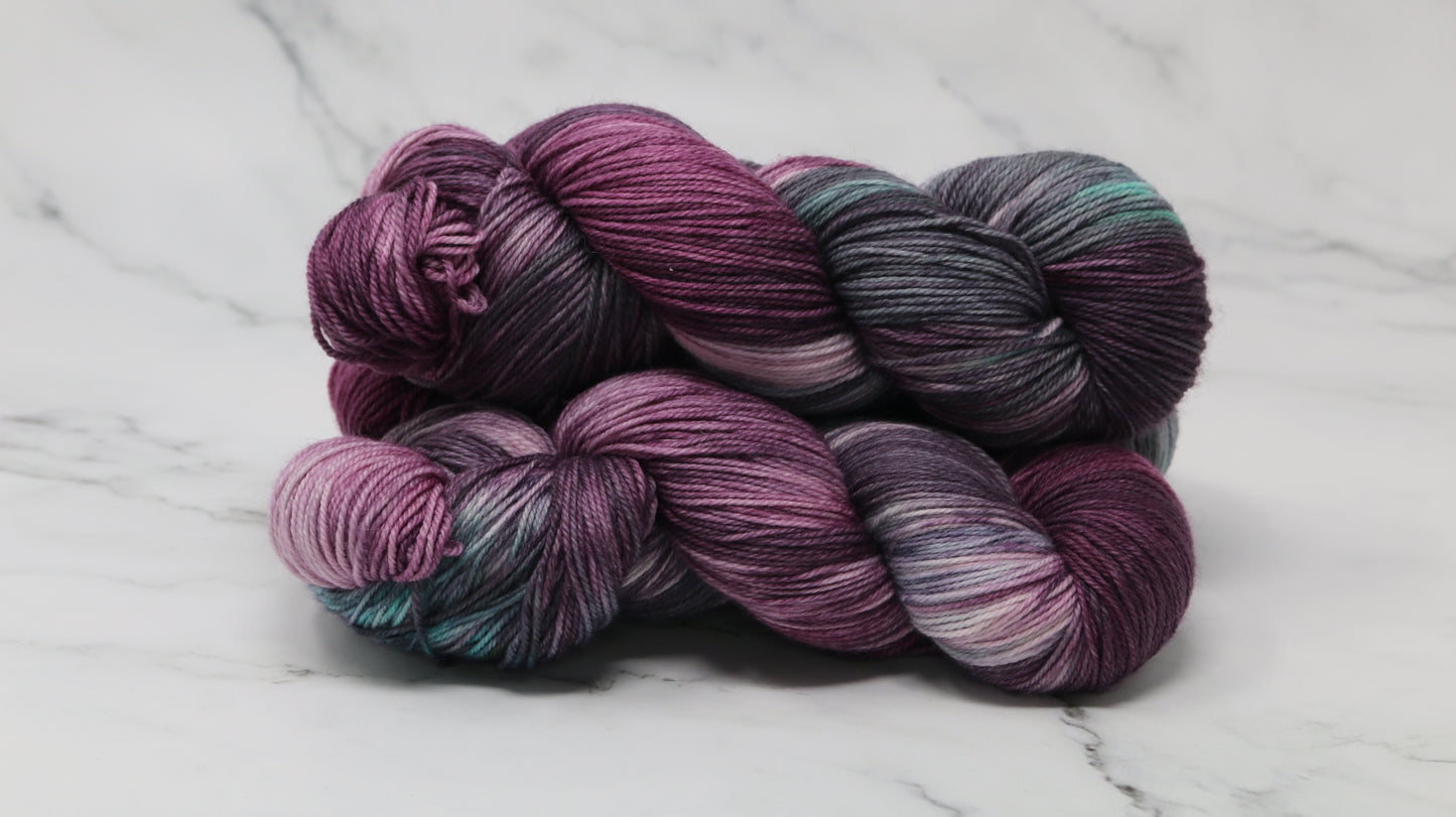 Three skeins of variegated yarn skeins in shades of purple, pink, green and dark gray