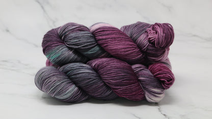Three skeins of variegated yarn skeins in shades of purple, pink, green and dark gray