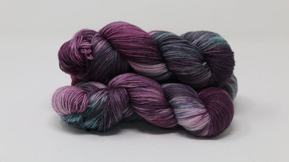 Three skeins of variegated yarn skeins in shades of purple, pink, green and dark gray
