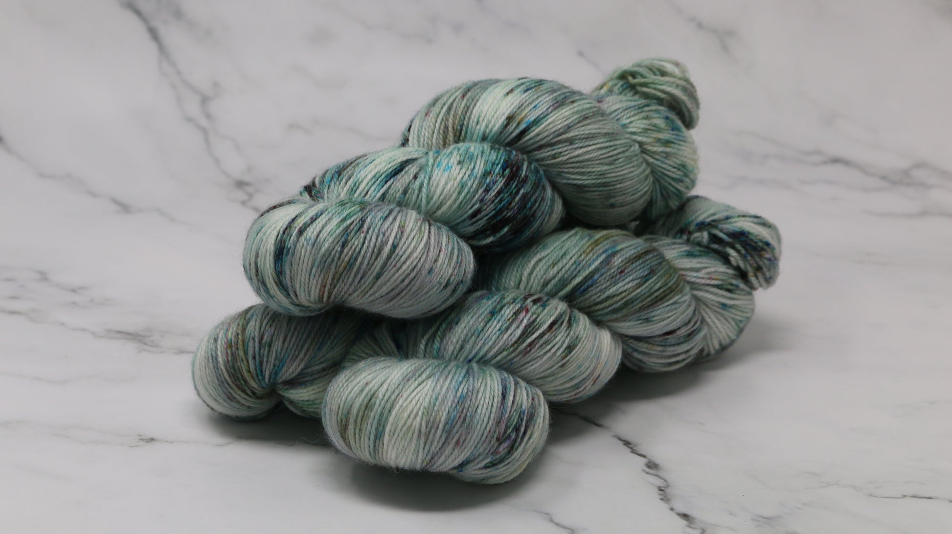3 skeins of speckled yarn in green, blue, pink, brown