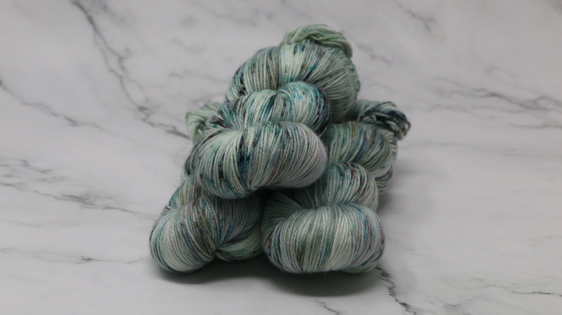 3 skeins of speckled yarn in green, blue, pink, brown
