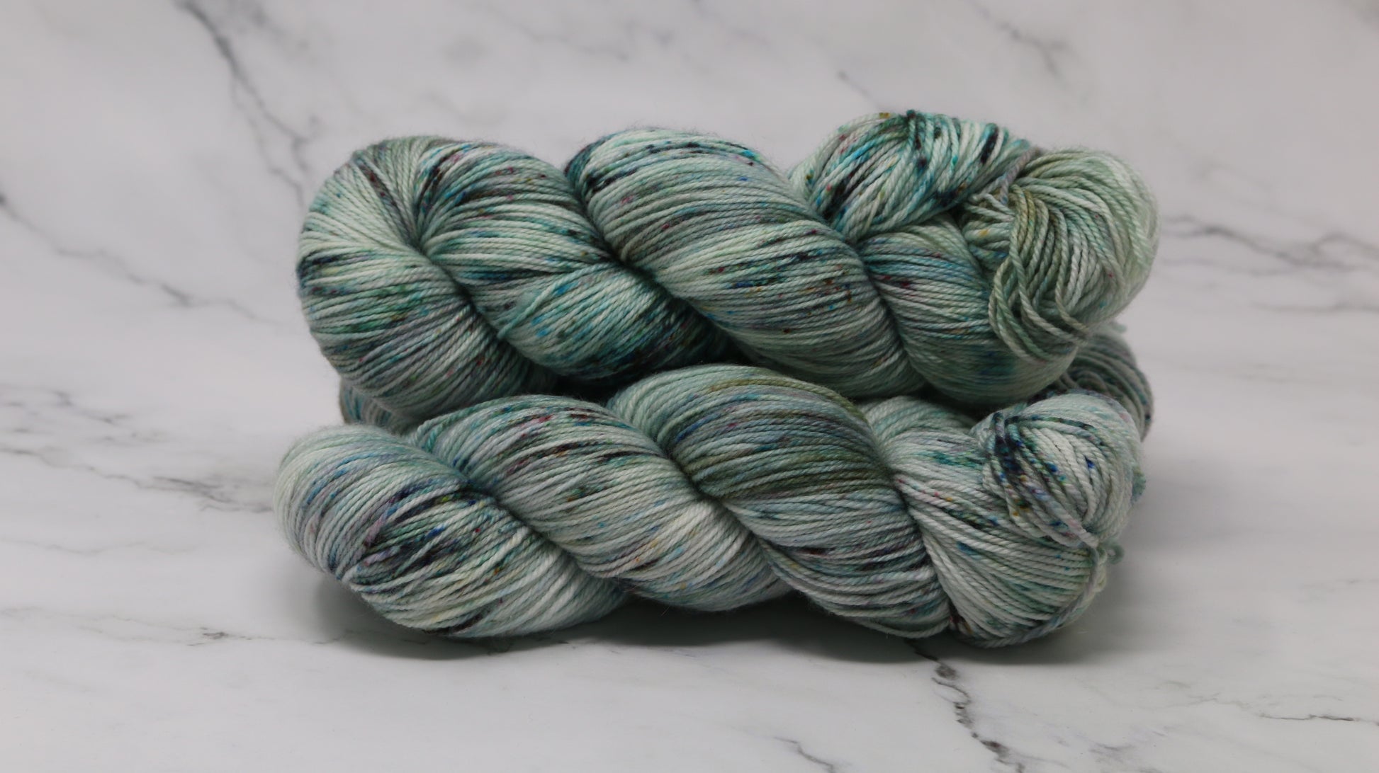 3 skeins of speckled yarn in green, blue, pink, brown