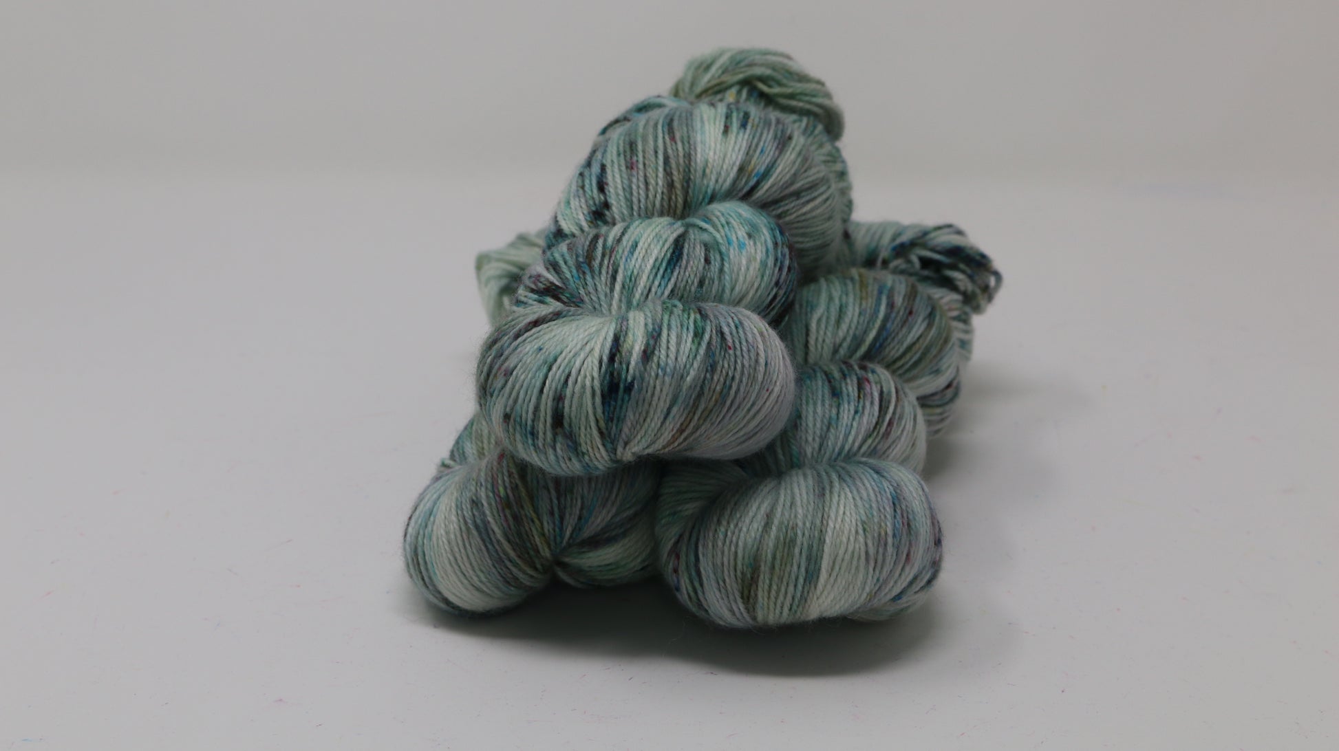 3 skeins of speckled yarn in green, blue, pink, brown