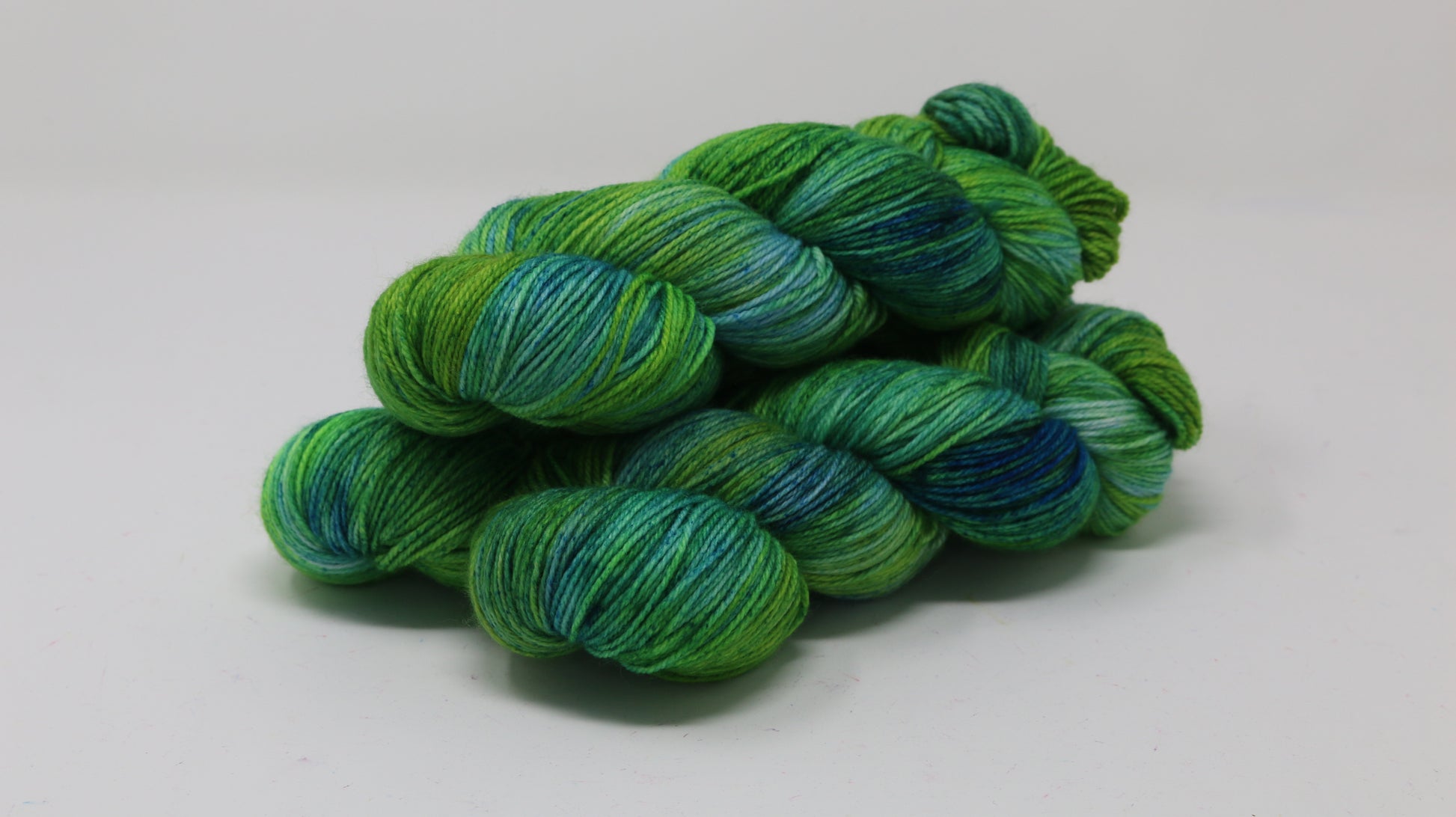 three skeins piled in tones of green and blue
