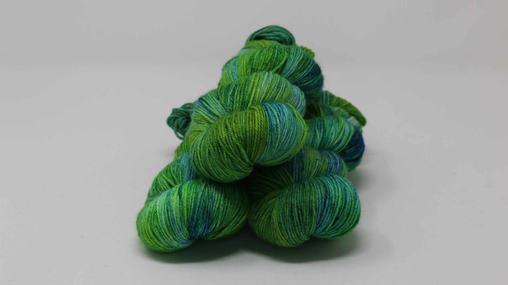three skeins piled in tones of green and blue
