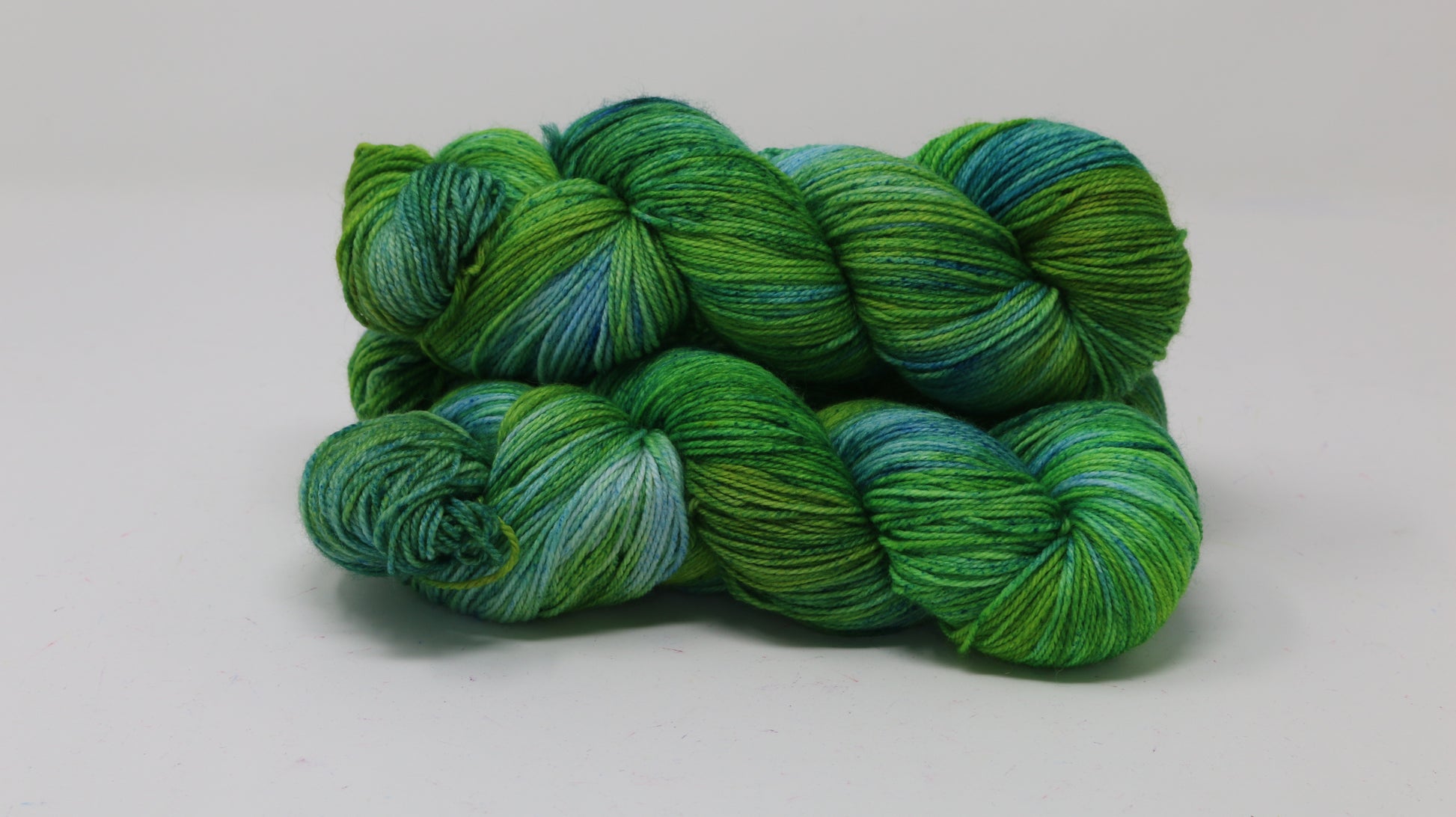three skeins piled in tones of green and blue