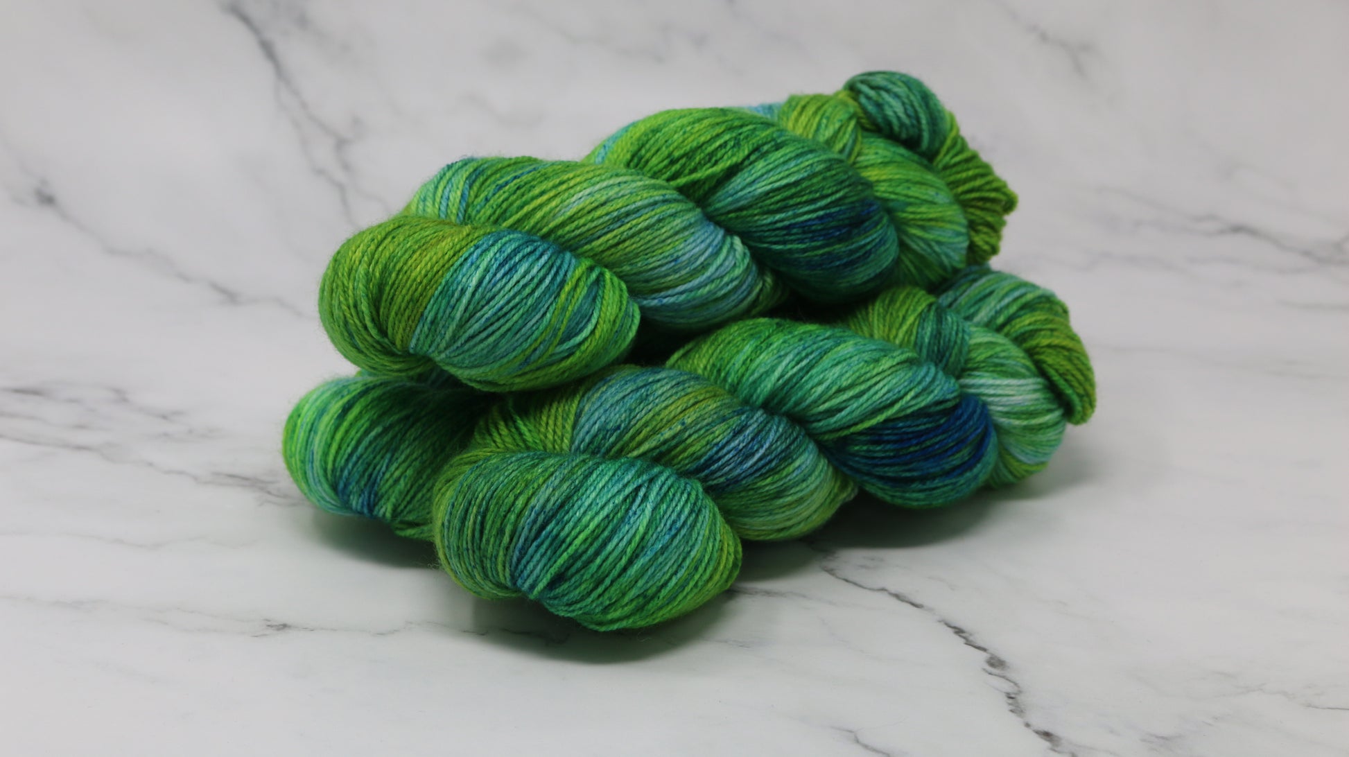 three skeins piled in tones of green and blue