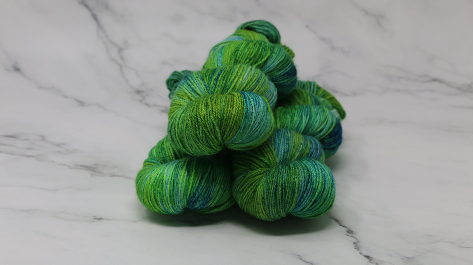 three skeins piled in tones of green and blue