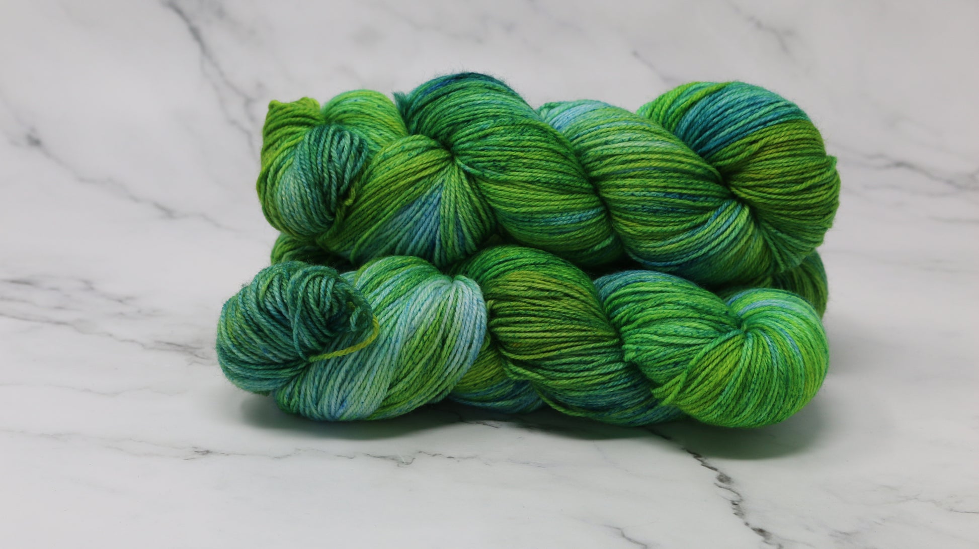 three skeins piled in tones of green and blue