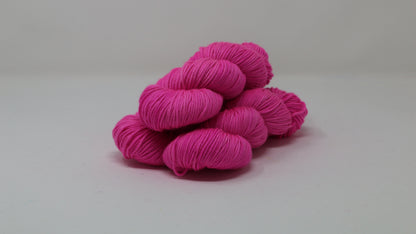 3 skeins of hot pink yarn displayed on a white surface and background
