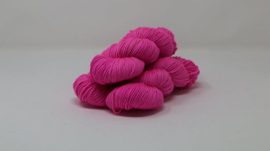 3 skeins of hot pink yarn displayed on a white surface and background