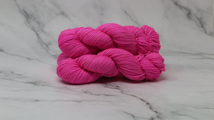 3 skeins of hot pink yarn displayed on a white marble surface and background