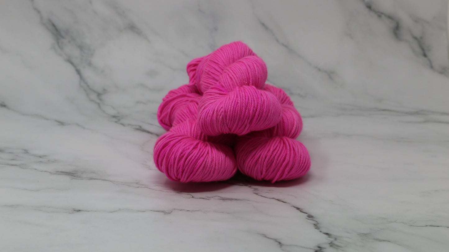 3 skeins of hot pink yarn displayed on a white marble surface and background