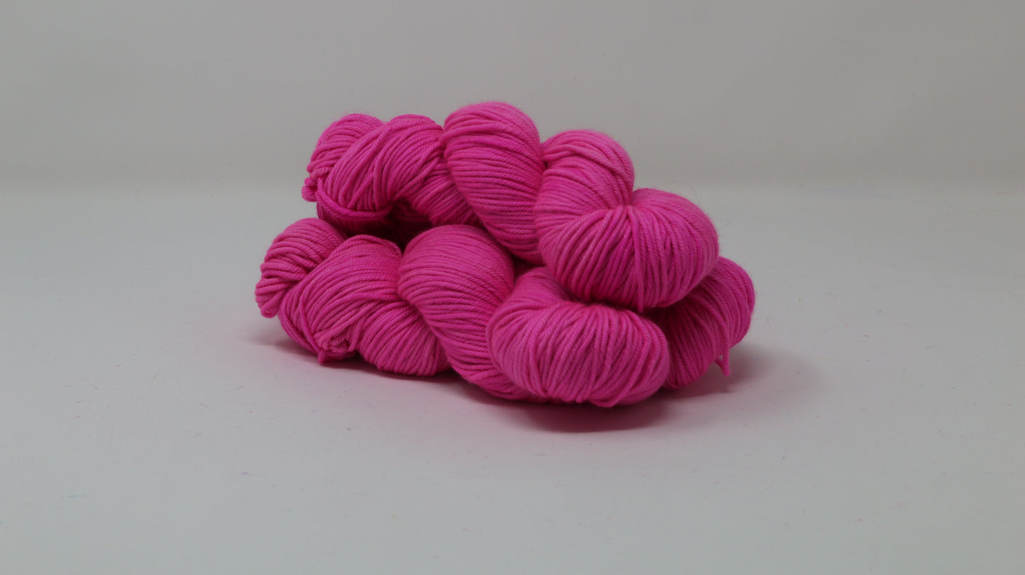 3 skeins of hot pink yarn displayed on a white surface and background