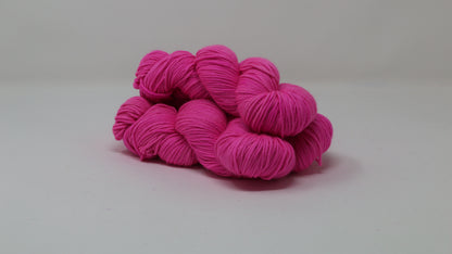 3 skeins of hot pink yarn displayed on a white surface and background