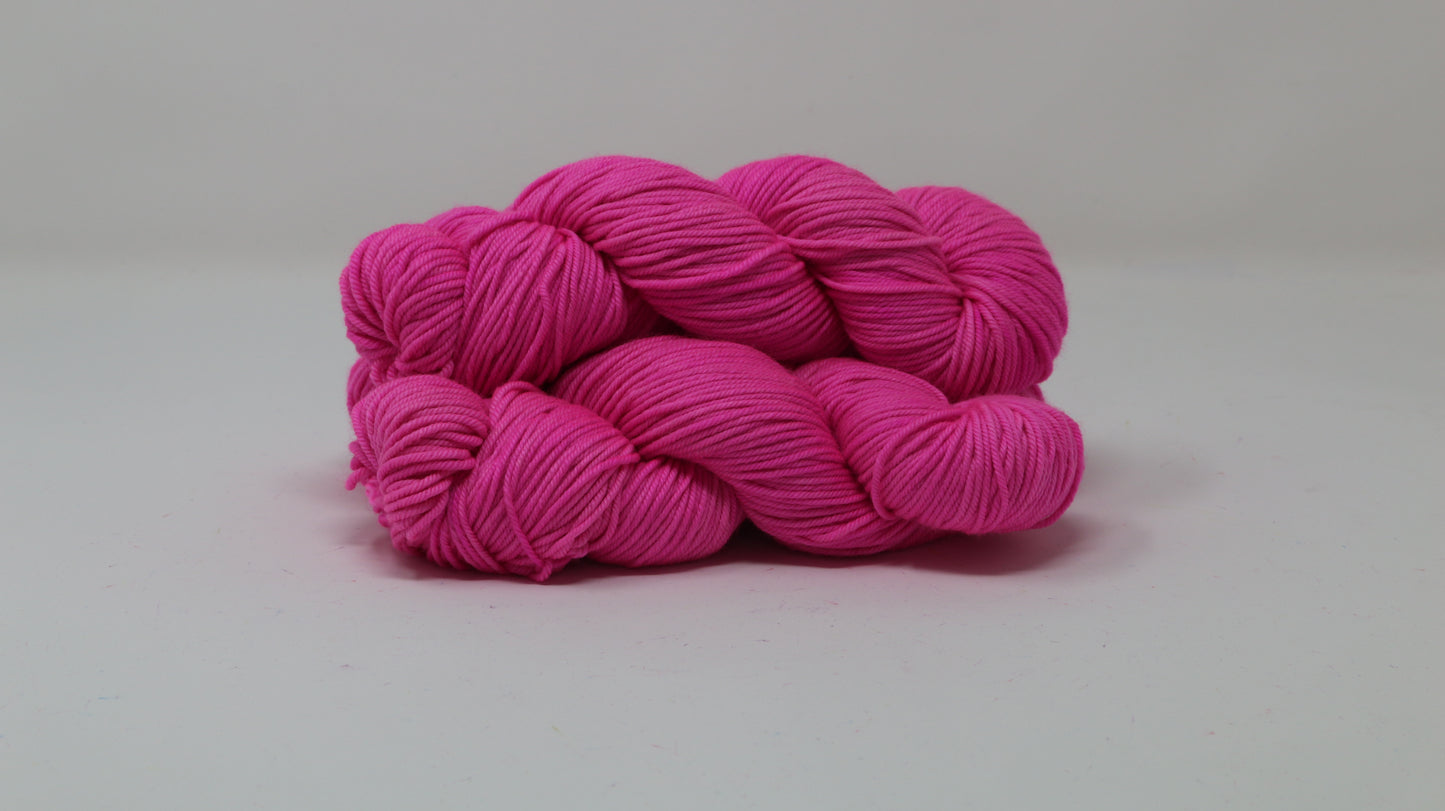 3 skeins of hot pink yarn displayed on a white surface and background