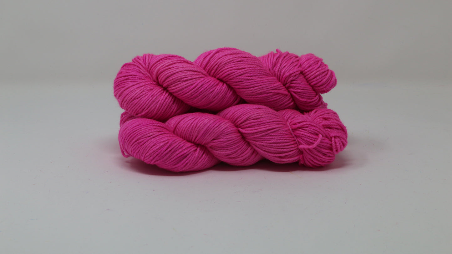 3 skeins of hot pink yarn displayed on a white surface and background