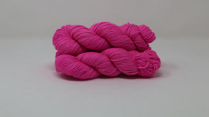 3 skeins of hot pink yarn displayed on a white surface and background