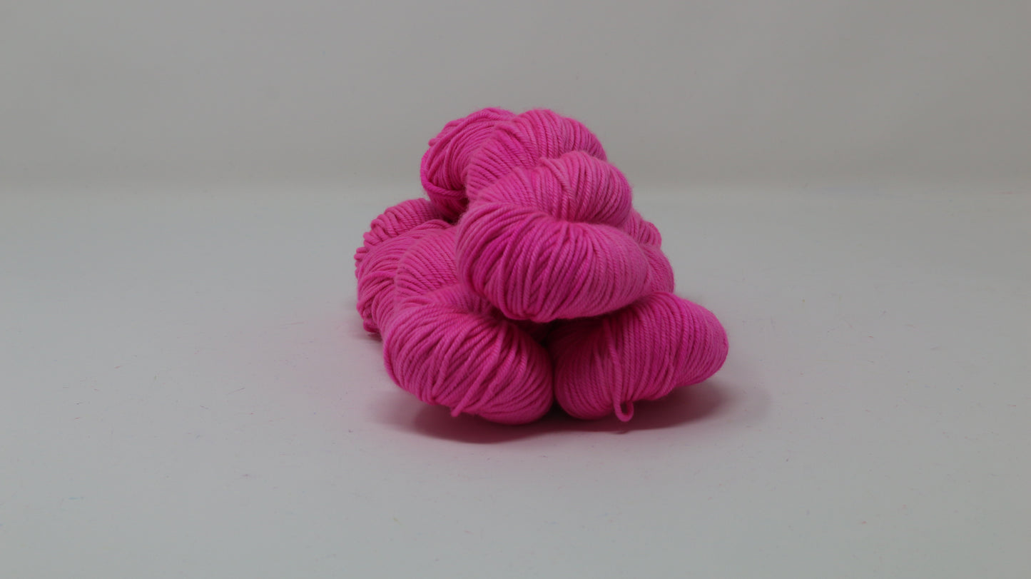 3 skeins of hot pink yarn displayed on a white surface and background