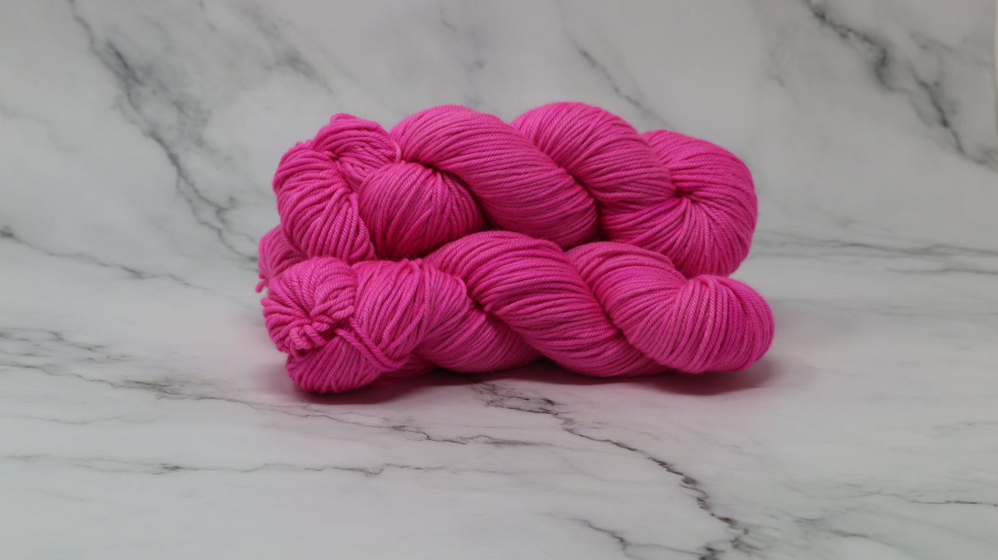 3 skeins of hot pink yarn displayed on a white marble surface and background
