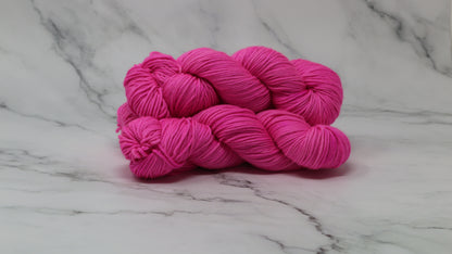 3 skeins of hot pink yarn displayed on a white marble surface and background