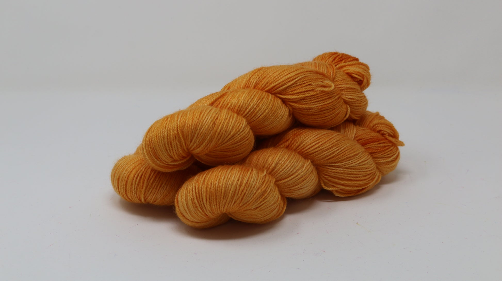 3 skeins of orange yarn on a white surface and background