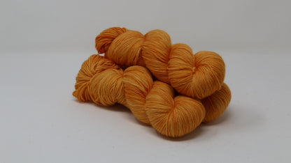 3 skeins of orange yarn on a white surface and background