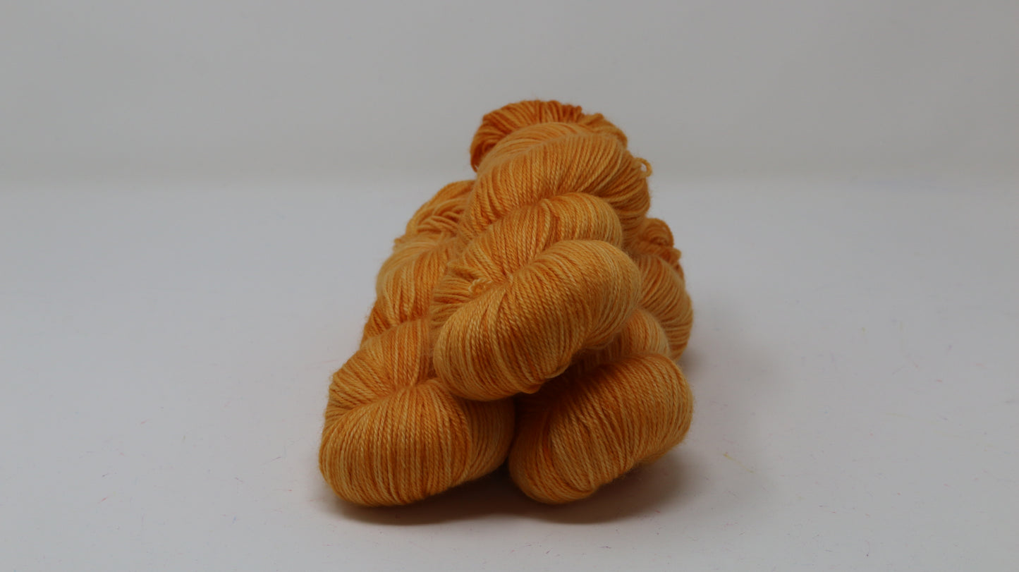 3 skeins of orange yarn on a white surface and background