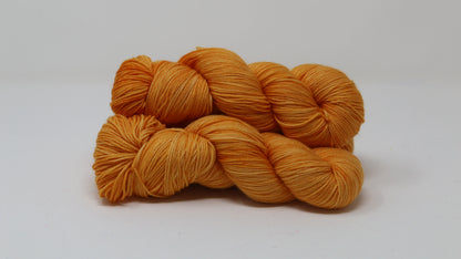 3 skeins of orange yarn on a white surface and background