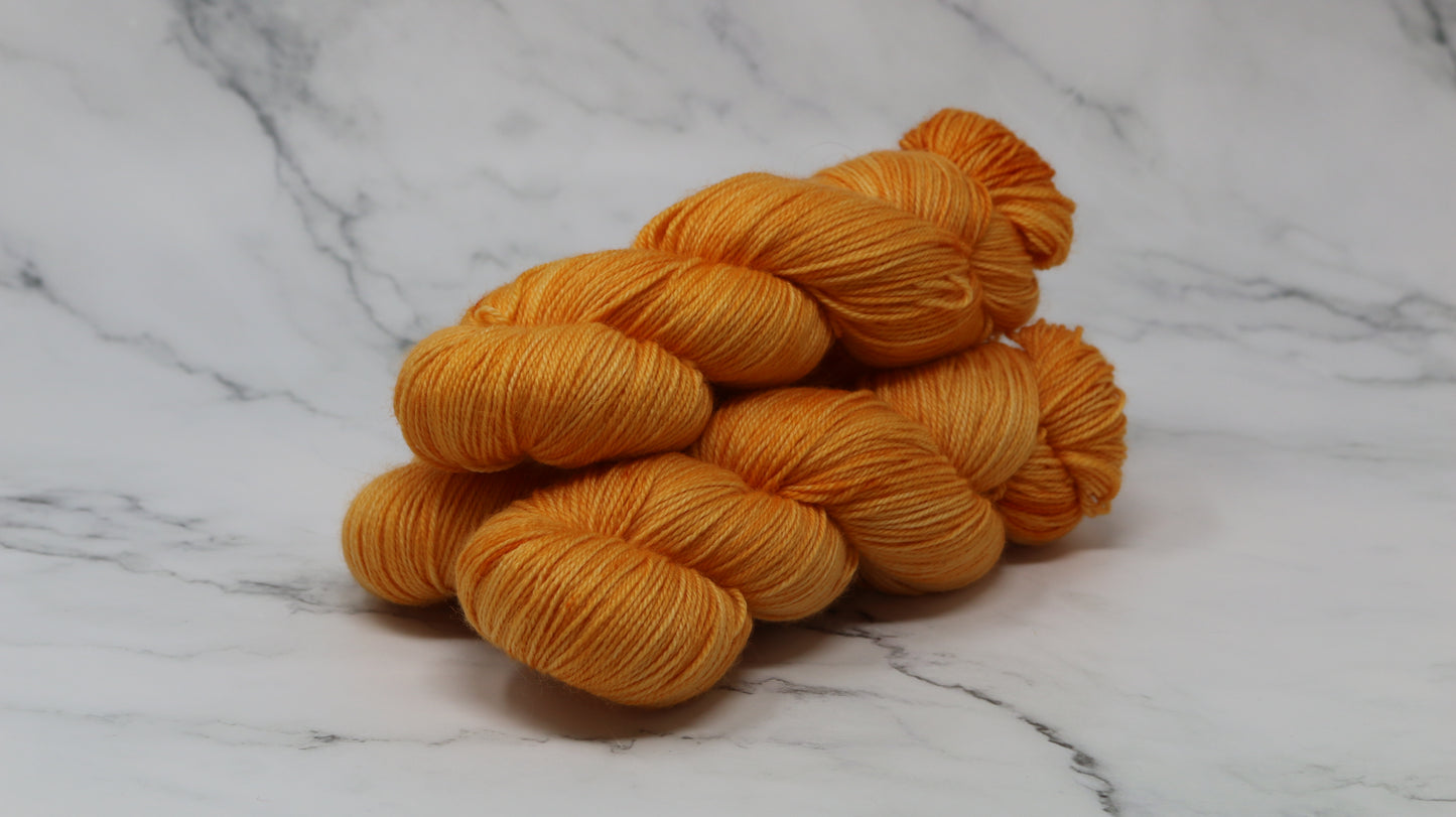 3 skeins of orange yarn on a white marble surface and background
