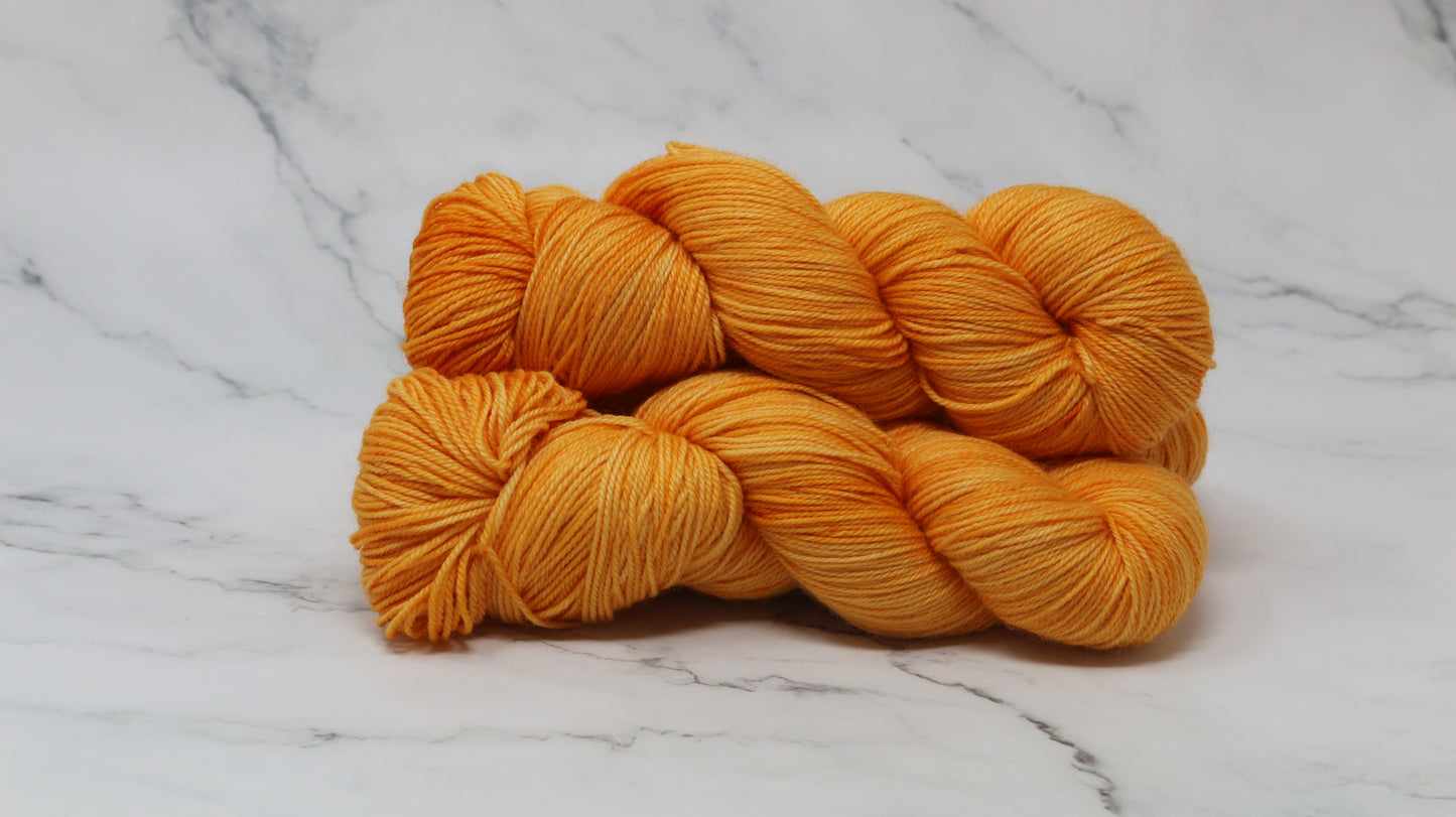 3 skeins of orange yarn on a white marble surface and background