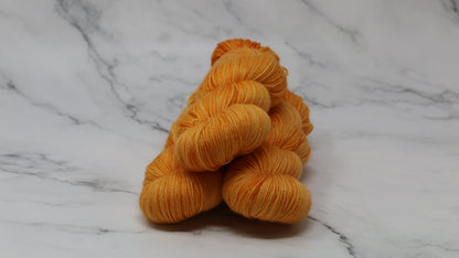 3 skeins of orange yarn on a white marble surface and background
