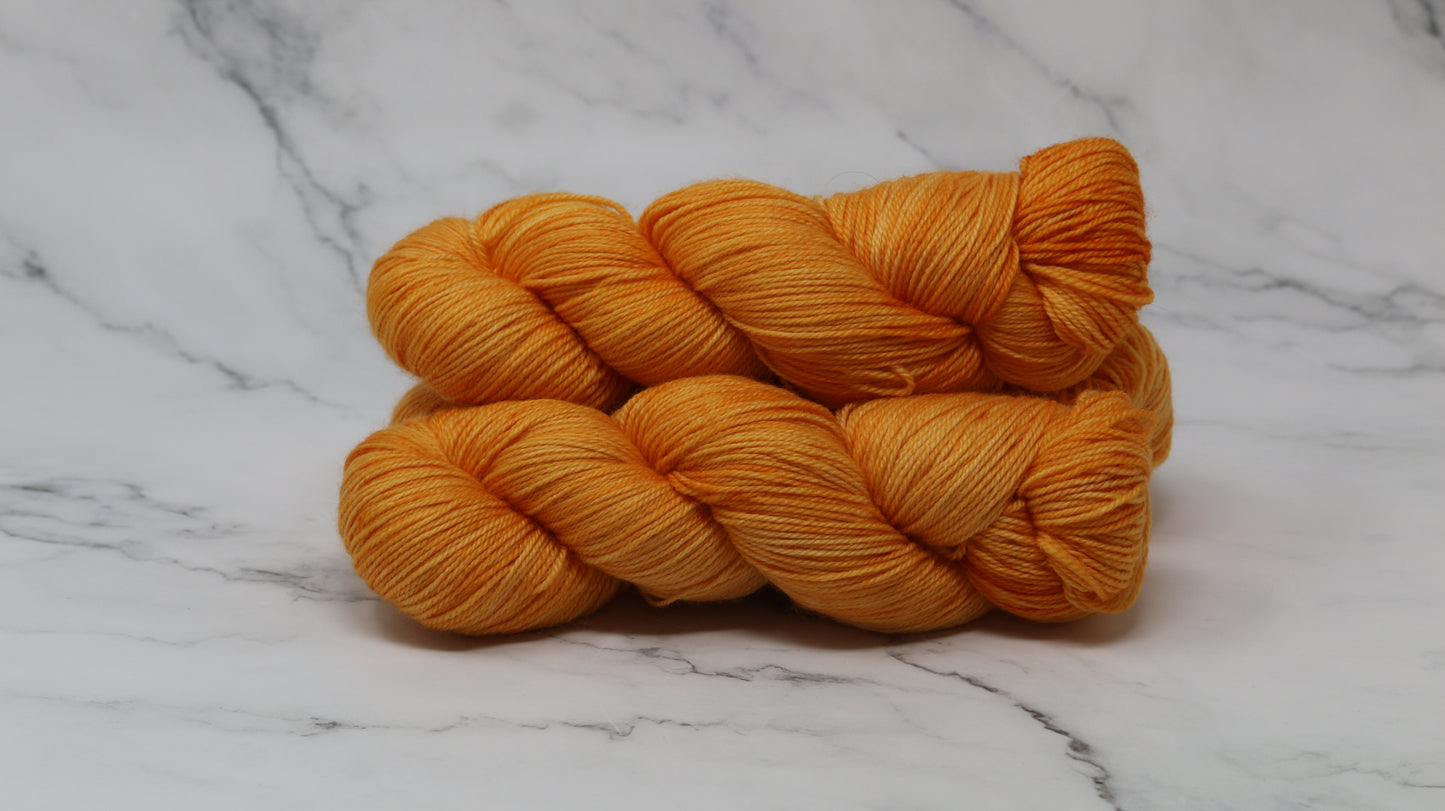 3 skeins of orange yarn on a white marble surface and background