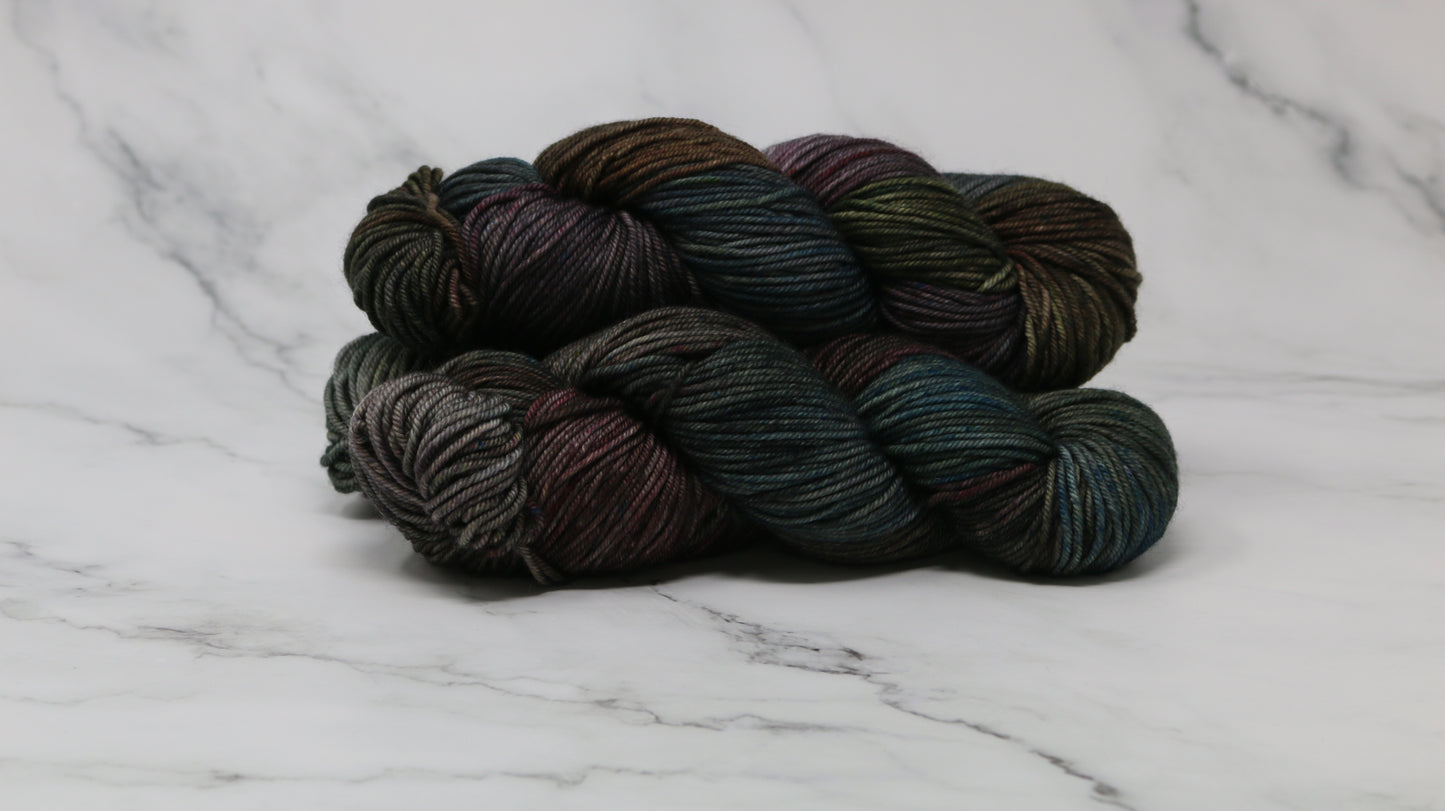 Three skeins of multicolored yarn on a white marble surface
