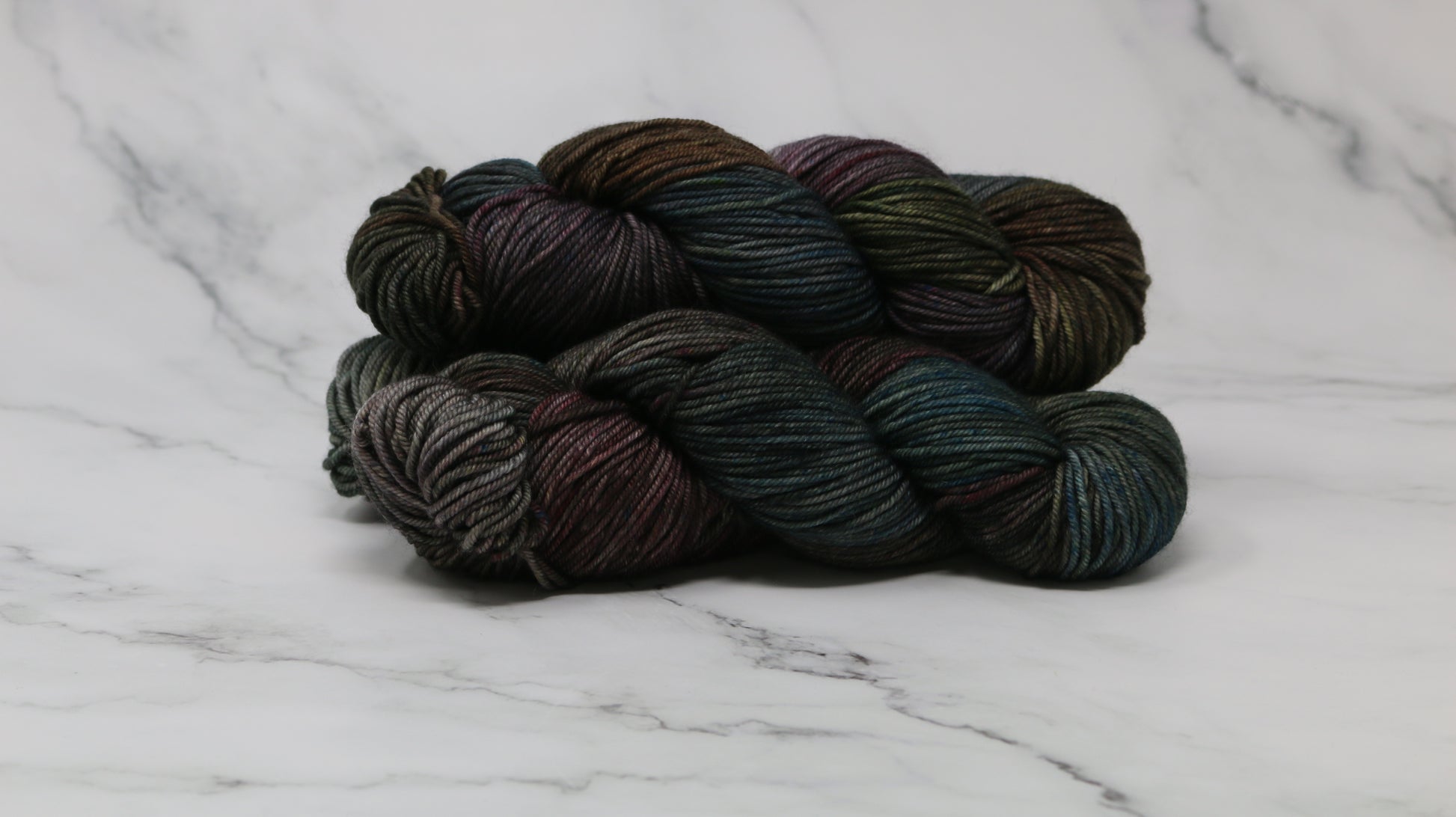 Three skeins of multicolored yarn on a white marble surface
