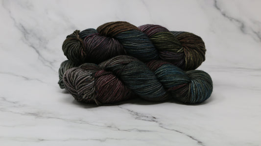 Three skeins of multicolored yarn on a white marble surface