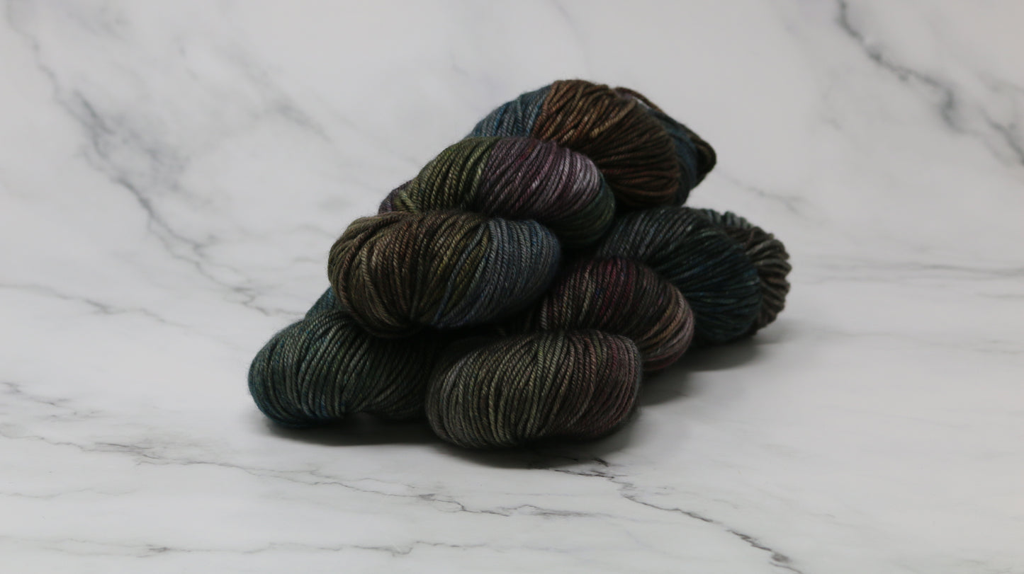 Three skeins of multicolored yarn on a white marble surface