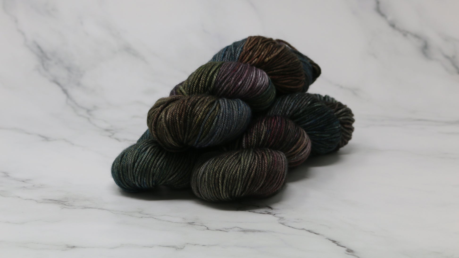 Three skeins of multicolored yarn on a white marble surface