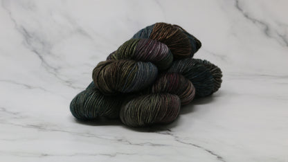 Three skeins of multicolored yarn on a white marble surface