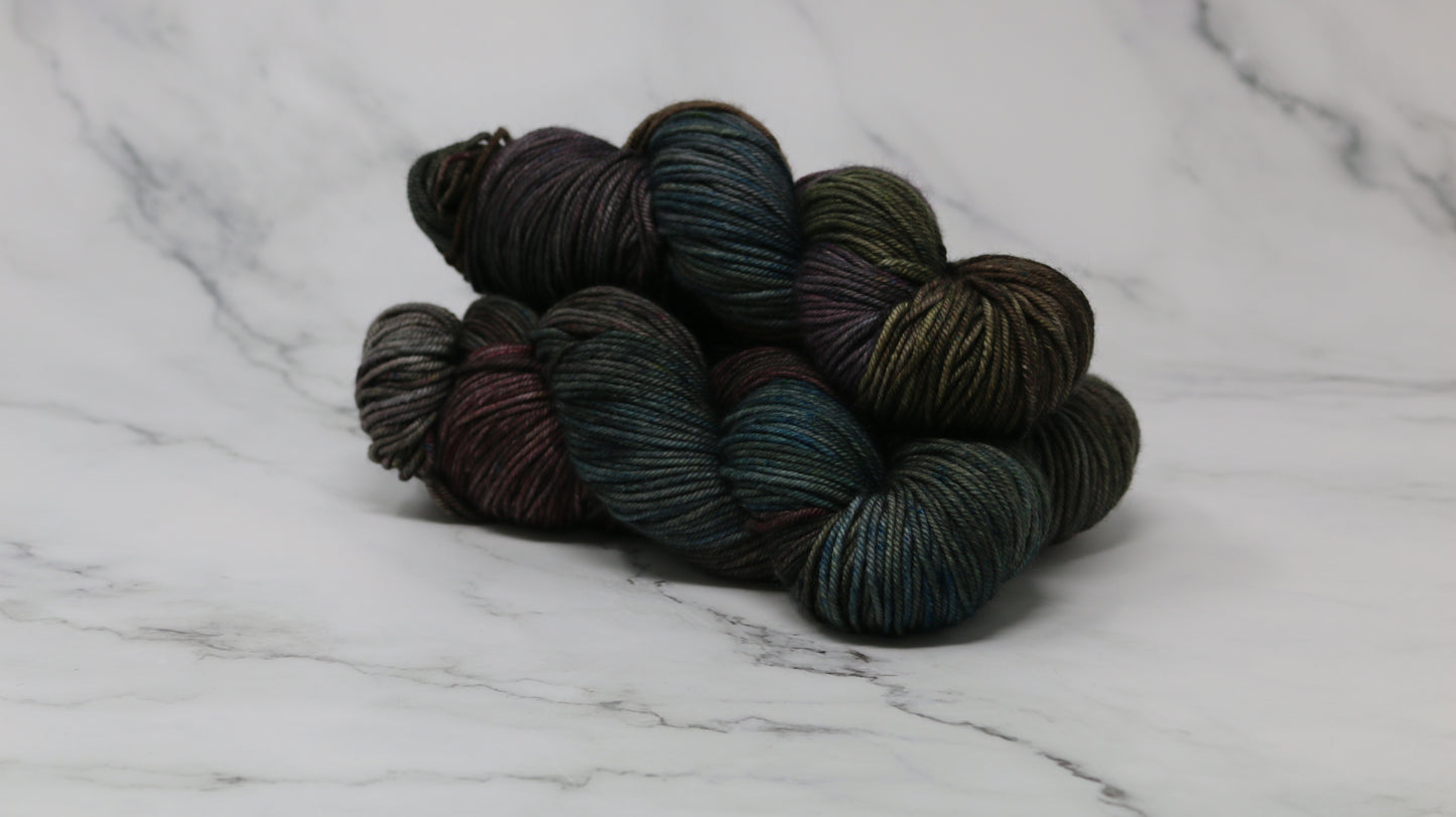 Three skeins of multicolored yarn on a white marble surface