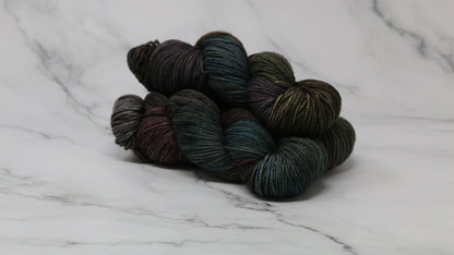 Three skeins of multicolored yarn on a white marble surface