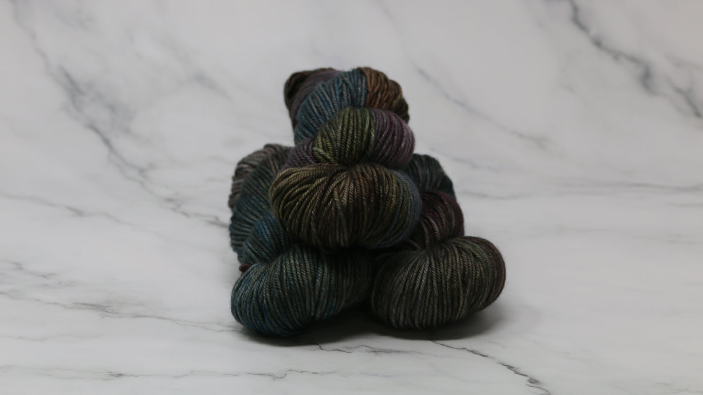 Three skeins of multicolored yarn on a white marble surface