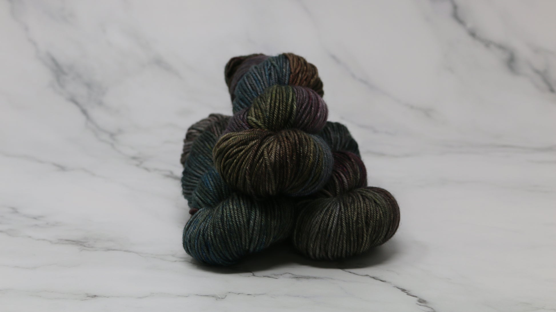 Three skeins of multicolored yarn on a white marble surface